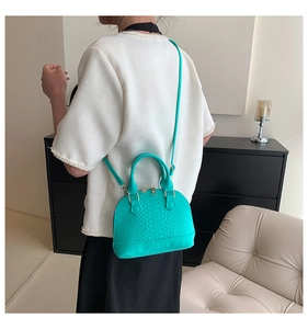 Detail view of teal faux snakeskin shell bag with gold zippers and detachable strap