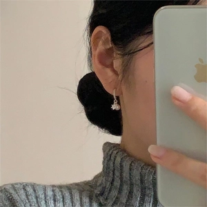 Detail of star-shaped silver earring with white pearl drop shown on a model