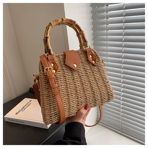 Detail of woven straw handbag with bamboo handle, leather trim and gold hardware