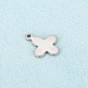 Macro view of a silver clover-shaped stainless steel pendant with a smooth polished finish
