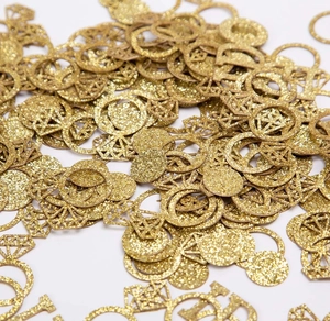 Close-up of golden glitter diamond ring confetti scattered for wedding table decoration