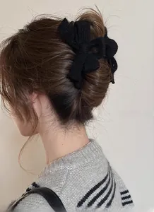 Close-up of black knitted bow hair claw clip styled on a low bun for autumn