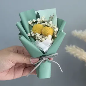 Close-up of a mini flower bouquet with yellow Billy balls and white baby's breath flowers