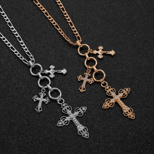 Close-up of silver and rose gold cross pendants with pavé crystals on Figaro chains
