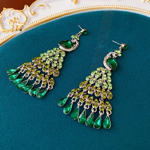Détail de boucles d'oreilles paon vintage avec strass verts et finition plaquée or