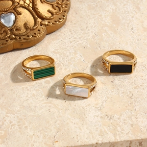 Detailed top view of gold rings with malachite, marble and onyx inlays on marble surface