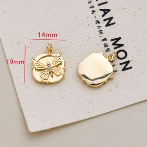 Detail shot of a 14x19mm gold butterfly charm with zircon inlay on a canvas bag