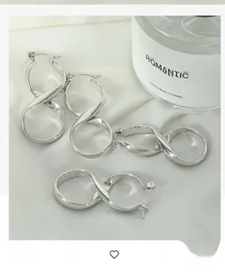 Detailed view of silver infinity twist earrings on soft silk fabric background