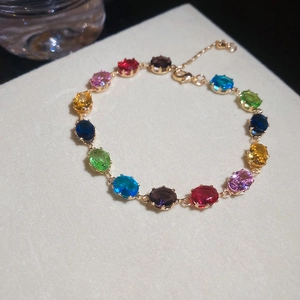 Detailaufnahme eines bunten Zirkonarmbands mit ovalen Edelsteinen in Goldfassung