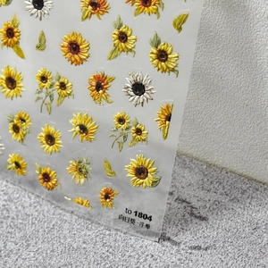 Detail shot of 3D embossed sunflower and daisy nail art stickers showing texture and depth