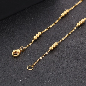 Elegant gold beaded stainless steel chain necklace for women shown on a dark surface