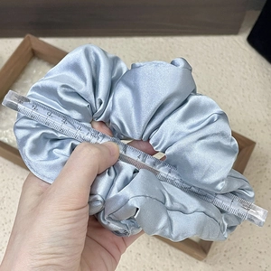 Detail view of large light blue satin scrunchie showing 12-13cm diameter with a ruler