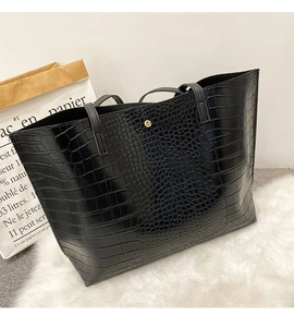 Close-up of black crocodile embossed tote bag with magnetic metal clasp and textured finish