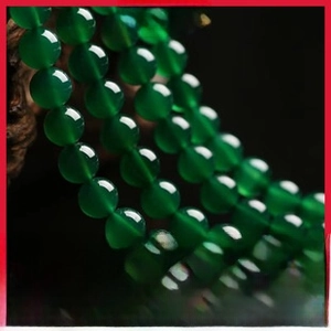 Macro detail of polished green agate round beads with smooth texture and emerald luster