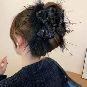 Detail of elegant black sequined hair claw clip with feather trim worn on a bun hairstyle