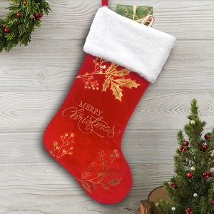 Detail of red velvet Christmas stocking with white fur trim and golden Merry Christmas print