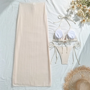 Flat lay detail of a beige waffle knit bikini set with matching long mesh cover-up skirt