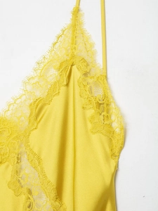 Détail de la bordure en dentelle jaune et du tissu satiné sur cette robe à bretelles
