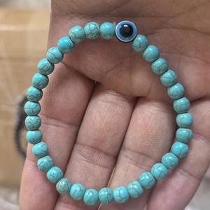 Detail of beaded turquoise bracelet with a central blue evil eye charm for men