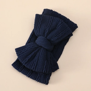 Detail of navy blue knitted baby headband featuring a large textured double layer bow