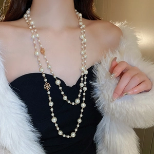 Detail of double-layer long pearl necklace featuring gold roses and coin charms on chain