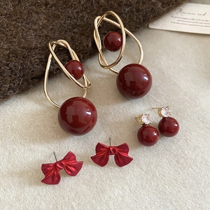 Detail view of vintage red pearl and bow earring set with gold accents on beige felt