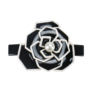 Detail of camellia hair clip with black petals, white edges, and a central pearl