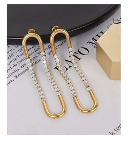 Detailed view of U-shaped gold earrings with zircons on elegant black ceramic tray