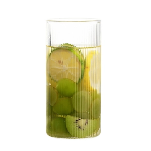 Vaso de vidrio de borosilicato con rayas verticales y frutas frescas sobre blanco