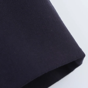 Macro close-up of dark navy twill fabric texture for preppy style pleated dress