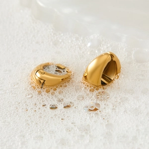 Polished gold stainless steel hoop earrings in minimalist water foam display