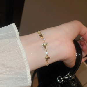 Close-up of gold heart-shaped bracelet with cubic zirconia on a woman's wrist