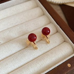 Macro detail of red pearl clip-on earrings on a vintage jewelry box cushion