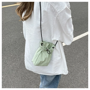 Detail of light green nylon mini crossbody bag with drawstring closure and slim cord strap