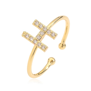 Macro view of gold letter H ring with cubic zirconia inlay on a white reflective base