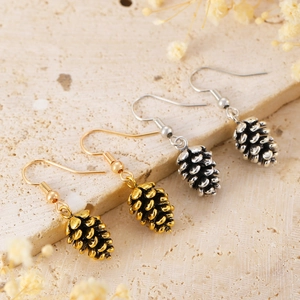 Macro detail of vintage bohemian pine cone earrings in antique gold and silver finishes