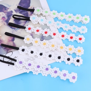 Detail view of six colorful lace daisy headbands with elastic bands on a light blue background