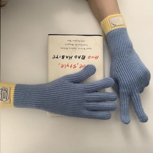 Detail of blue knitted gloves with yellow cuffs and a woven label for winter warmth