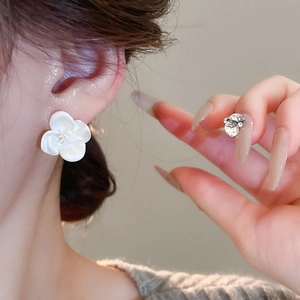 Close-up of elegant white zircon flower stud earrings worn on ear for stylish fashion