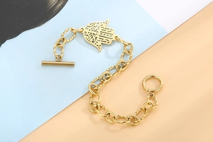 Gros plan du pendentif main de Hamsa sur un bracelet gourmette en acier doré avec fermoir