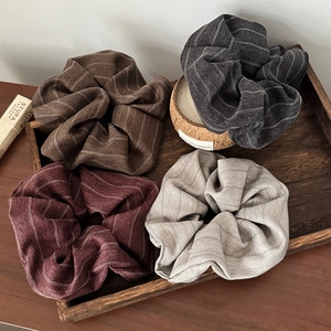 Striped fabric scrunchies set in neutral tones arranged on a wooden tray