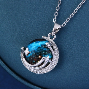 Macro shot of silver crescent moon necklace with a deep blue galaxy sphere and stars