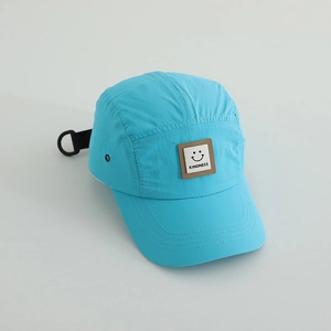 Detail of blue quick-dry 5-panel cap featuring a smiley kindness patch and metal eyelets