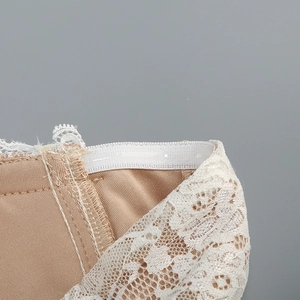 Detailed close-up of lace trimming and reinforced stitching on a beige corset dress