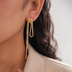 Close-up of golden chain knot fringe earrings on a model with fine metallic texture