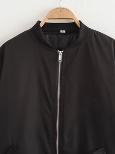 Détail d'un blouson bomber noir avec fermeture éclair en métal et col côtelé sur cintre