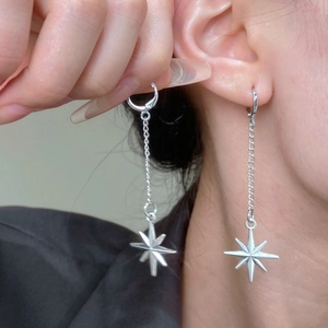 Gros plan de longues boucles d'oreilles argentées avec pendentifs étoiles et chaînes