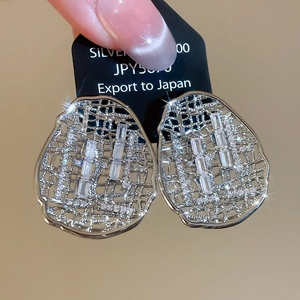 Détail macro de boucles d'oreilles ovales argentées ajourées avec incrustation de zircon