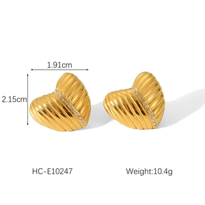 Macro detail of gold heart earrings showing textured pattern and rhinestone inlay