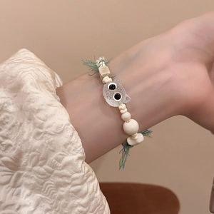Detailed shot of handmade ceramic beaded bracelet with clear kitten charm and blue tassels